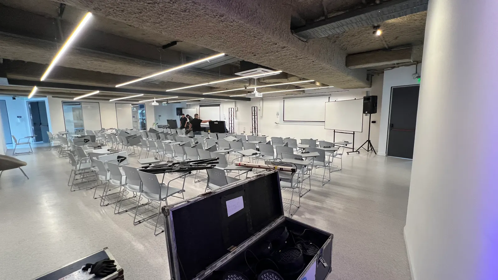 Salón antes del montaje, con luz blanca de servicio y los cases de transporte