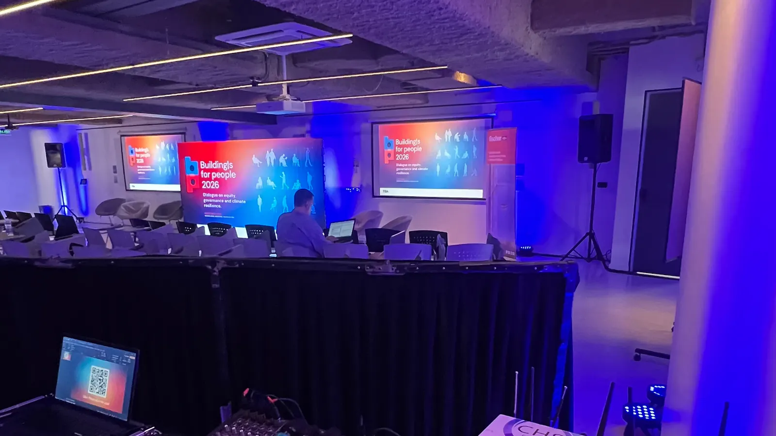 El mismo salón listo para el evento, con luz azul, pantallas encendidas y el puesto de control