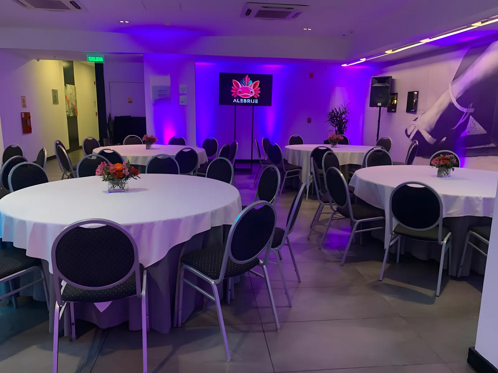 Salón con mesas redondas y luz violeta sobre las paredes