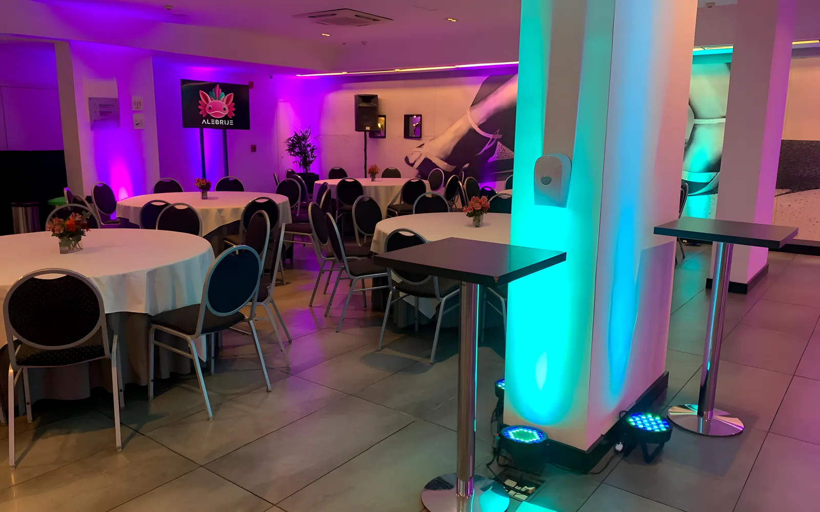 Salón con iluminación ámbar sobre los cortinados y una mesa larga armada