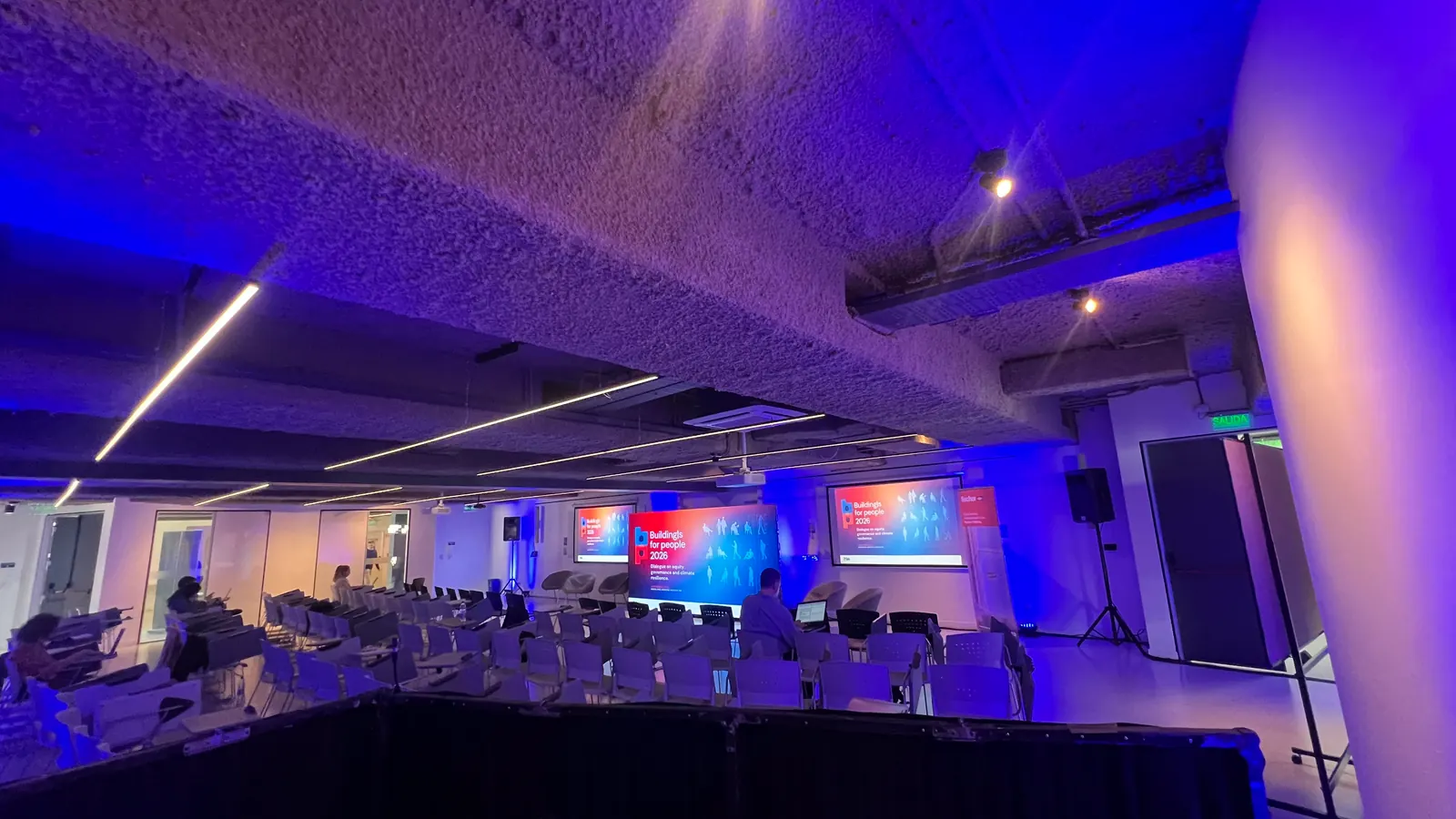 Sala lista para un evento vista desde el puesto de control, con luz azul y pantallas
