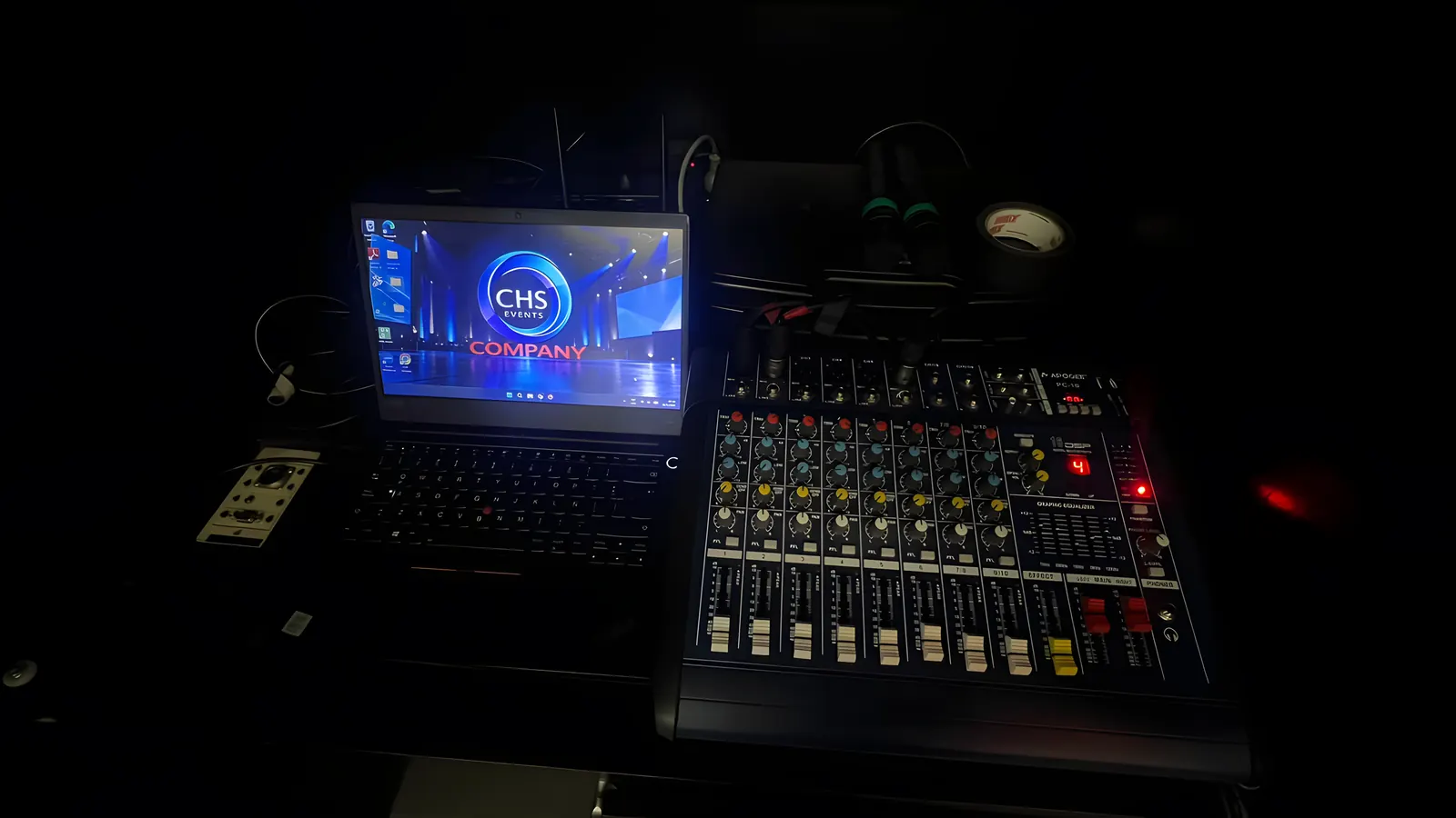 Consola de sonido y notebook con el logo de CHS Company en el puesto de control